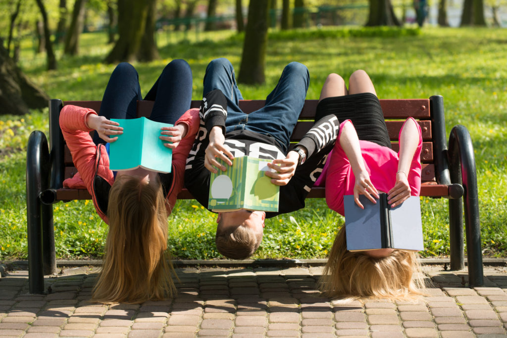 Młodzież czyta książki w parku na ławce