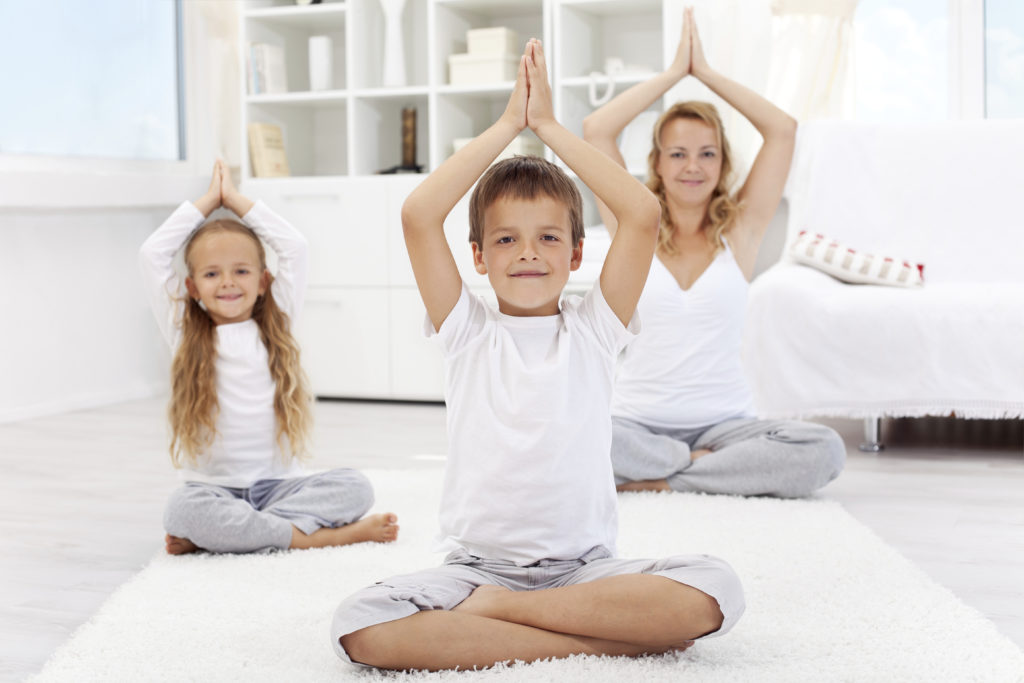 Happy balanced life - woman and kids doing yoga exercise at home - focus on boy